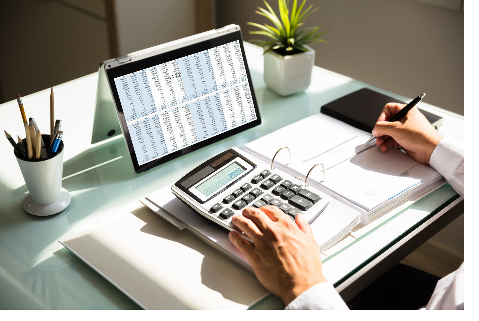 Comptable analysant des tableaux financiers sur un ordinateur portable avec une calculatrice